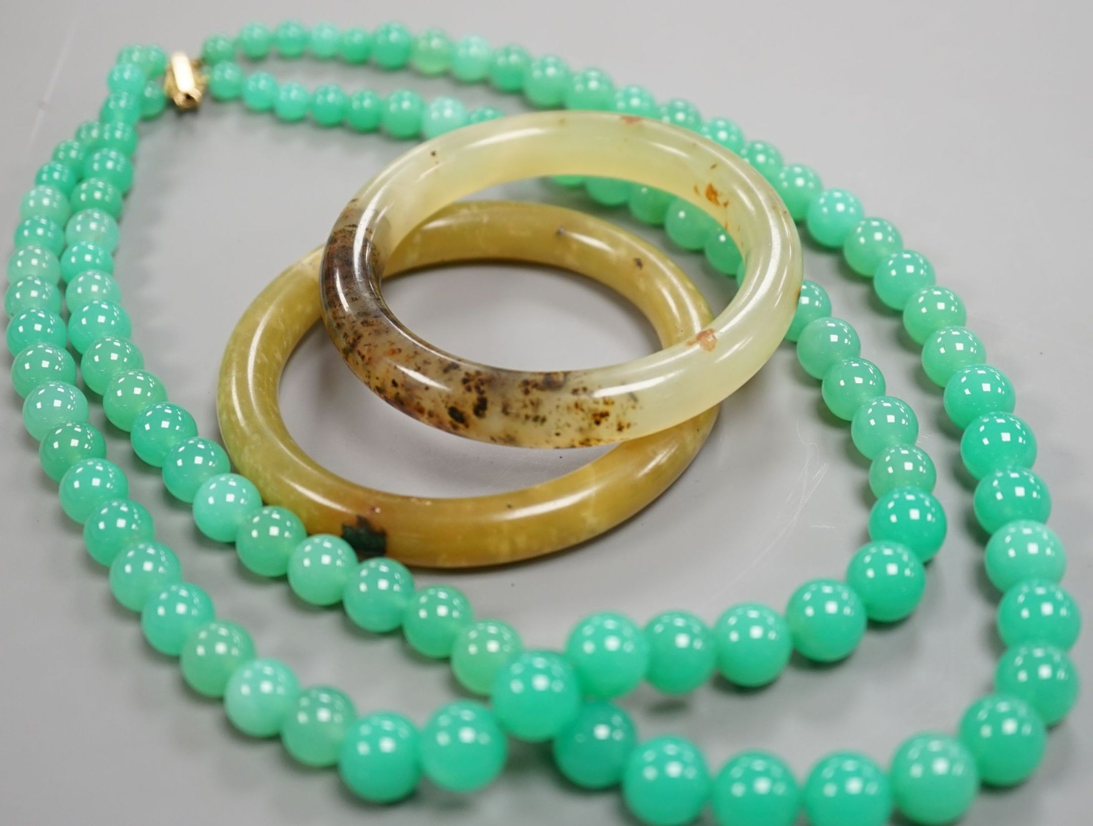 A double strand chrysoprase bead necklace with 750 yellow metal clasp, 50cm and two bowenite bangles.